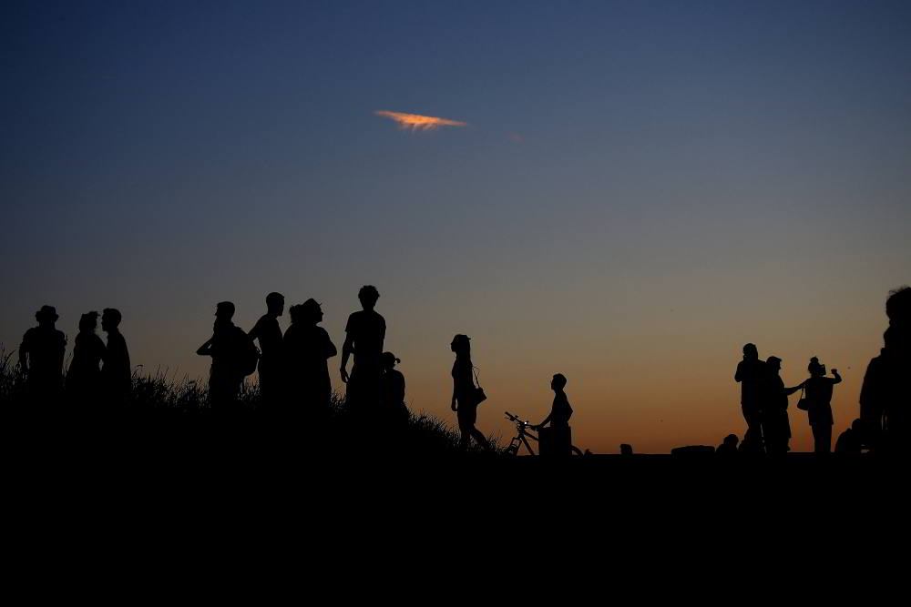 Silhouetten von Personen vor Abendhimmel